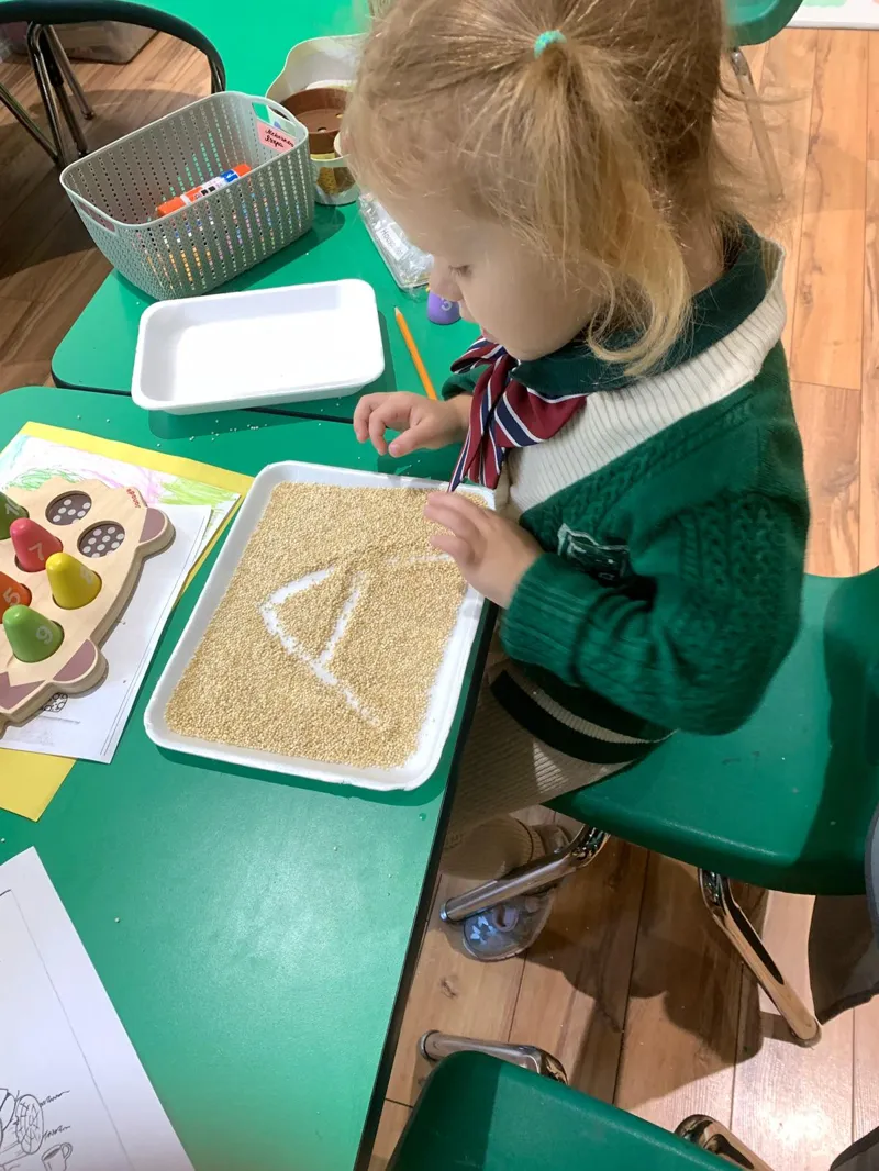 Child engaged in sensory letter tracing activity demonstrating integrated growth learning at Alderwood Academy